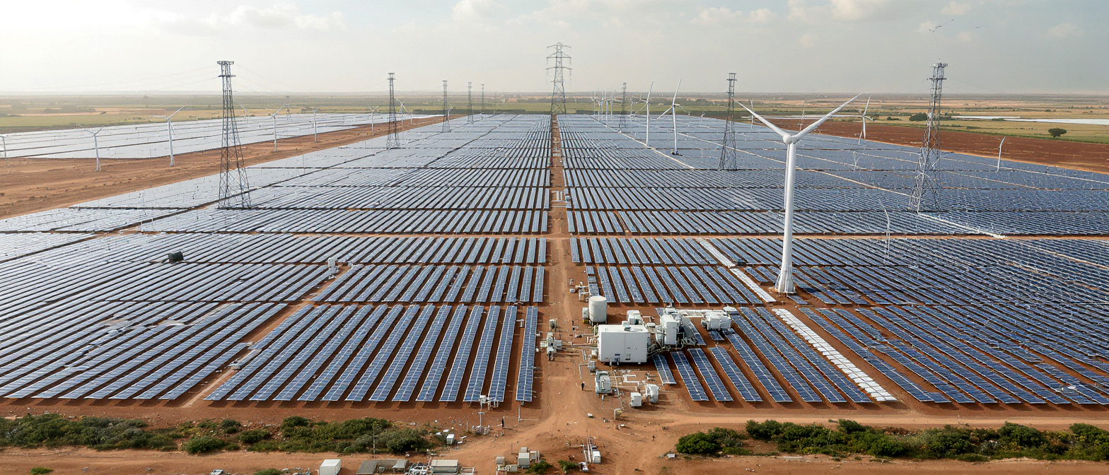 Renewable energy installation in West Africa featuring solar fields, hybrid power systems, and engineers monitoring digital equipment for clean industrial development.